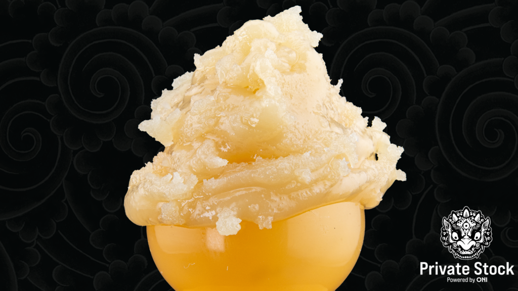 Pale yellow cannabis rosin displayed against a dark patterned background.