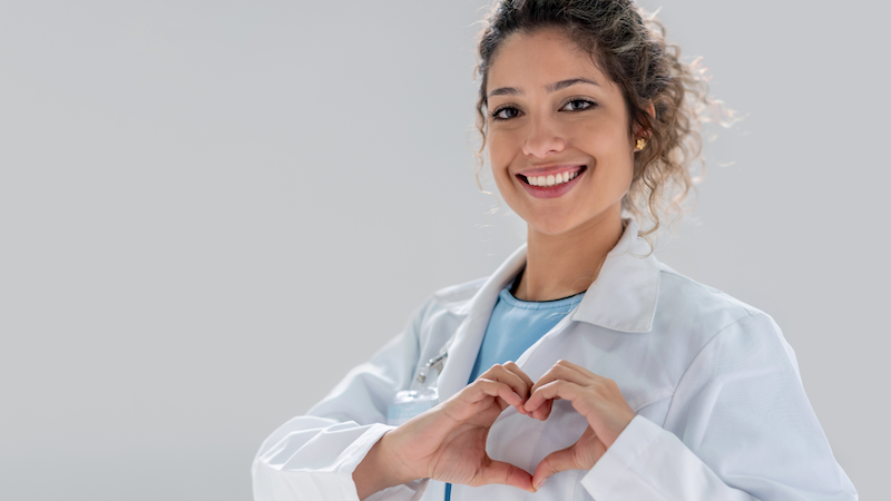 Smiling female healthcare professional wearing a white medical coat.
