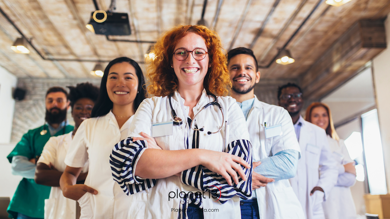 Female doctor with curly red hair standing with a team of healthcare professionals.