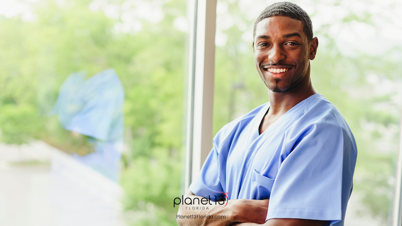 Smiling male healthcare professional wearing blue scrubs and a stethoscope.
