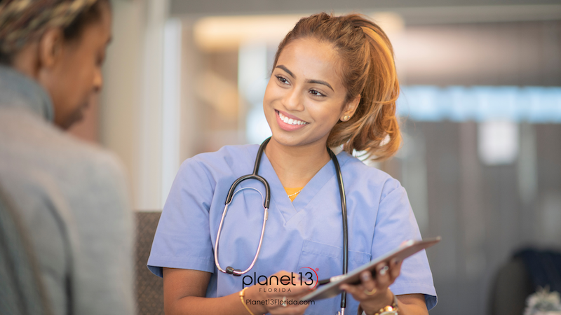 Smiling female healthcare professional wearing blue scrubs.