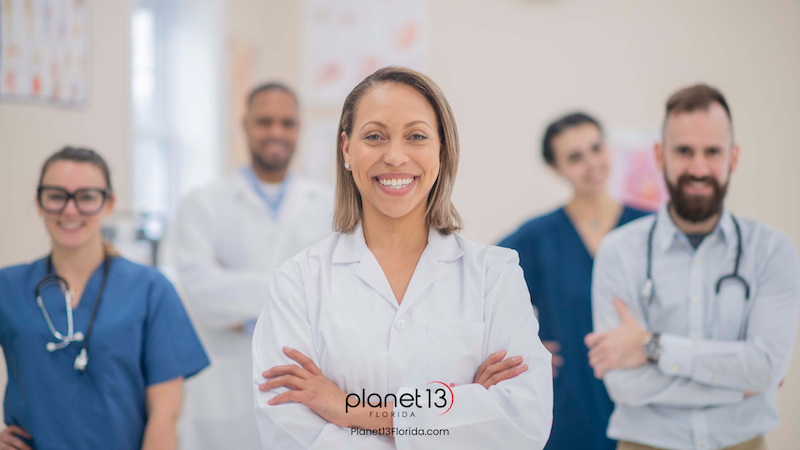 Smiling female doctor standing in front of medical colleagues.