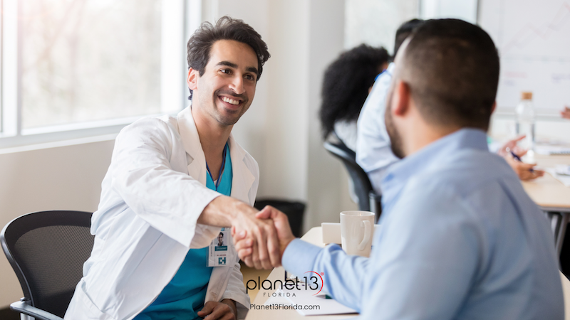 Male doctor speaking with a seated patient during a medical consultation.