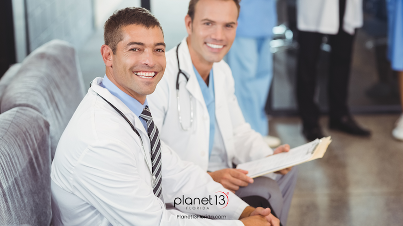 Male doctor smiling while speaking with a colleague in a medical office.