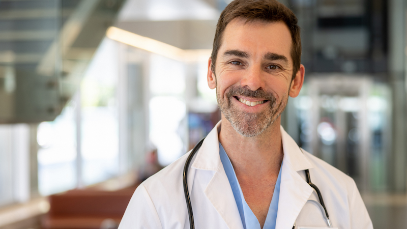 Smiling male doctor wearing a white coat in a medical office.