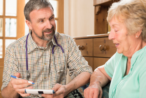 Doctor speaking with an older male patient during a medical consultation.