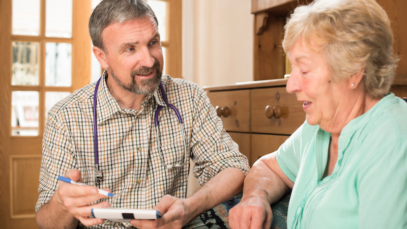 Doctor speaking with an older male patient during a medical consultation.